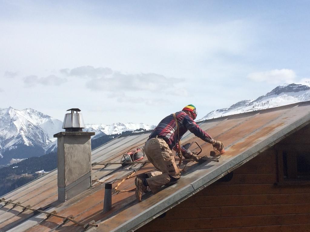 Gesicherter UNISEKON Mitarbeiter bei Höhenarbeiten auf einem Alpendach